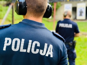 zdjęcie przedstawia zajęcia na strzelnicy otwartej podczas których instruktor stoi za strzelającym policjantem