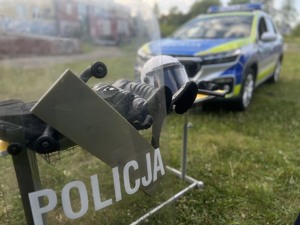 Na zdjęciu tarcza z napisem POLICJA a na dalszym planie radiowóz