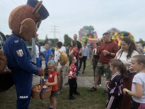 zdjęcie przedstawia maskotka policji wiewiórka rozdająca cukierki podczas festynu