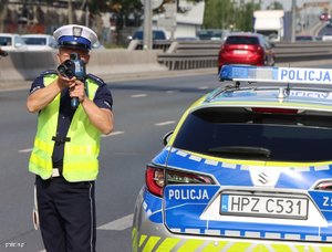 zdjęcie archiwalne pokazujące policjanta z drogówki kontrolującego prędkość, obok stoi policyjny radiowóz