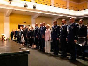 zdjęcie przedstawia gości i policjantów stojących w trakcie odgrywania przez orkiestrę hymnu