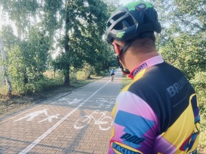 Na zdjęciu rowerzysta w kasku, patrzy w kierunku ścieżki rowerowej