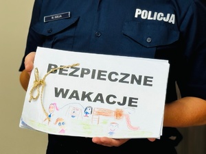 zdjęcie pokazuje policjantkę trzymającą w rękach prace plastyczne wykonane przez dzieci