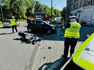 zdjęcie z miejsca wypadku - policjant opisuje uszkodzenia pojazdów uczestniczących w zdarzeniu