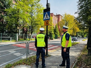 zdjęcie przedstawia policjantów z drogówki przy przejściu dla pieszych obok szkoły