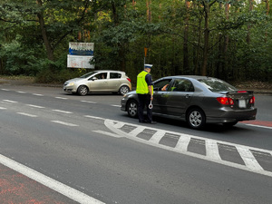 zdjęcie przedstawia policjanta z drogówki kontrolującego trzeźwość kierowcy