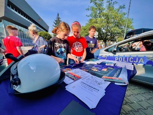 zdjęcie z festynu przedstawiające przygotowane przez policjantów stoisko profilaktyczne na którym dwie dziewczynki układają przygotowane puzle