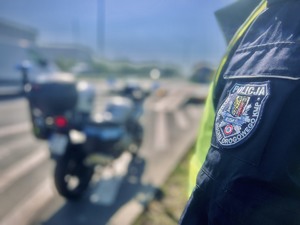 Zbliżenie na naszywkę z napisem Policja Ruda Śląska Wydział Ruchu Drogowego, w tle rozmyty motocykl policyjny