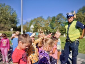 Dzieci wraz z umundurowanym policjantem w miasteczku ruchu drogowego