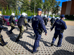 zdjęcie przedstawia szkolenie strażników granicznych - dwóch policjantów przy biegnących strażnikach