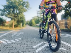 zdjęcie przedstawia wyznaczoną drogę rowerową i stojącego rowerzystę ze swoim jednośladem
