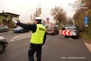 zdjęcie przedstawia policjanta z drogówki kierującego ruchem przy cmentarzu