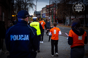 zdjęcie z akcji Świeć przykładem noś odblaski przedstawiające policjantów i wolontariuszy idących chodnikiem z odblaskami do kolejnych mieszkańców miasta