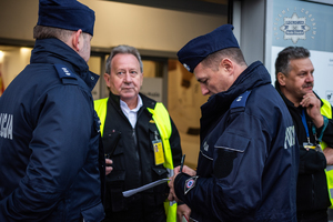 zdjęcie przedstawia policjantów rozmawiających z pracownikami ochrony przed wejściem do centrum handlowego