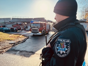 zdjęcie przedstawiające policjanta pilnującego dostępu do miejsca pożaru