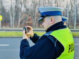 zdjęcie przedstawia policjantów nagrywających aparatem wykroczenia kierowców