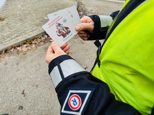 zdjęcie przedstawia policjanta trzymającego w rękach śmieszne karteczki z mikołajową reprymendą dla popełniających wykroczenie