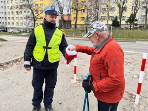 zdjęcie przedstawia policjanta wręczającego pieszemu cukierka za przestrzeganie przepisów