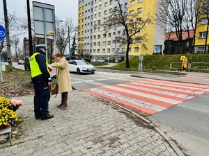 zdjęcie przedstawia policjanta przy przejściu dającego cukierka pieszej