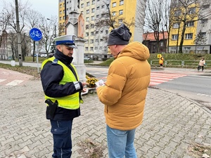 zdjęcie przedstawia policjanta wręczającego reprymendę pieszemu zamiast cukierka