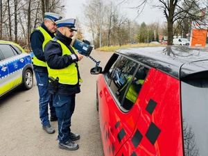 zdjęcie przedstawia policjantów w trakcie kontroli pojazdu którego kierująca przekroczyła prędkość