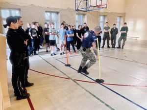 uczniowie oraz umundurowani policjanci przyglądają się jak instruktor prezentuje tor przeszkód