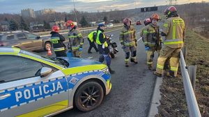 zdjęcie przedstawia miejsce wypadku na którym widać policjantów i strażaków