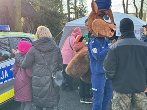 zdjęcie przedstawia ludzi odwiedzających policyjne stoisko i maskotkę rudzkiej policji sierżant rudą