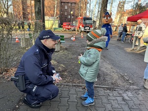 zdjęcie przedstawia policjanta kucającego przy małym chłopcu, który pyta o jego pracę