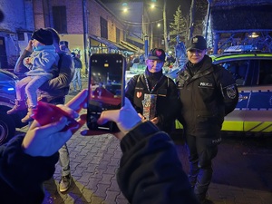 zdjęcie przedstawia policjantkę i wolontariuszkę oraz kolejną dziewczynę robiącą im zdjęcie telefonem