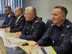 zdjęcie przedstawia siedzących przy stole konferencyjnym przedstawicieli miasta i policjantów