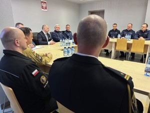 zdjęcie przedstawia salę odpraw, siedzących gości i prezydenta miasta podsumowującego wyniki policjantów