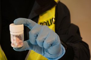 zdjęcie ilustracyjne - policjant trzymający w ręce słoiczek z substancją narkotyczną - foto z archiwum policji