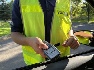 zdjęcie przedstawia widok policjanta trzymającego alkotest