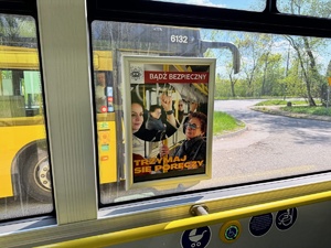 zdjęcie przedstawia wnętrze autobusu z widocznym plakatem kampanii, bądź bezpieczny trzymaj się poręczy