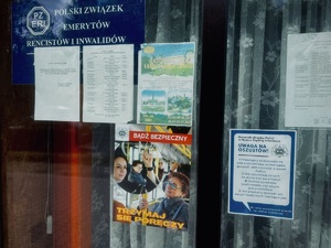 zdjęcie plakatów promocyjnych umieszczonych za szybą przy wejściu do klubu seniora