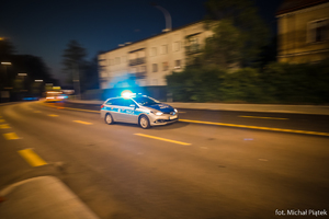 zdjęcie przedstawia jadący nocą policyjny radiowóz
