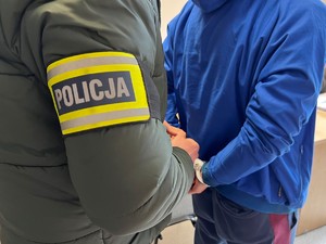 zdjęcie archiwalne przedstawiające policjanta kryminalnego zakładającego mężczyźnie kajdanki na ręce