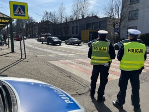 zdjęcie przedstawia policjantów z drogówki obserwujących ruch na jednej z ulic miasta