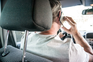 zdjęcie z wnętrza samochodu pokazujące kierowcę rozmawiającego przez telefon