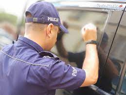 zdjęcie poglądowe - policjant zagląda do wnętrza samochodu