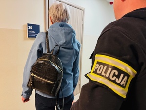 zdjęcie przedstawia policjanta z zatrzymaną kobietą przed wykonaniem zdjęć sygnaliztycznych