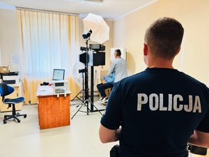 zdjęcie przedstawia policjanta z zatrzymaną kobietą przed wykonaniem zdjęć sygnaliztycznych
