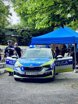 Policjant ruchu drogowego obok oznakowanego radiowozu