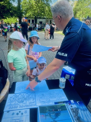 Policjant wręcza dzieciom kolorowanki