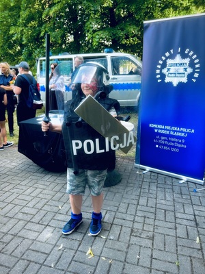 Dziecko w policyjnym sprzęcie pozuje do zdjęcia