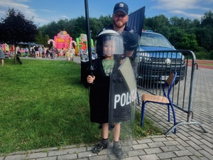 Policjant z dzieckiem ubranym w sprzęt policyjny, pozują do zdjęcia