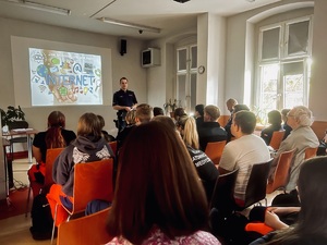 Zdjęcie przedstawia uczestników debaty oraz policjanta w trakcie przemówienia