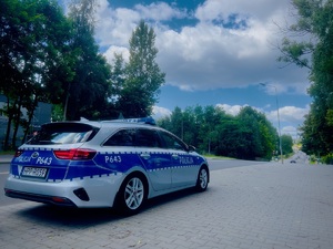 Zdjęcie przedstawia oznakowany radiowóz przy jezdni