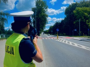Zdjęcie przedstawia policjantkę w trakcie pomiaru prędkości